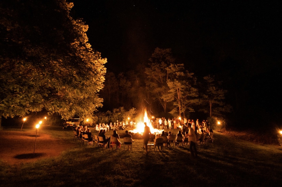 Gemeinschaft von Menschen sie am Waldrand im Kreis um ein grosses Feuer sitzen